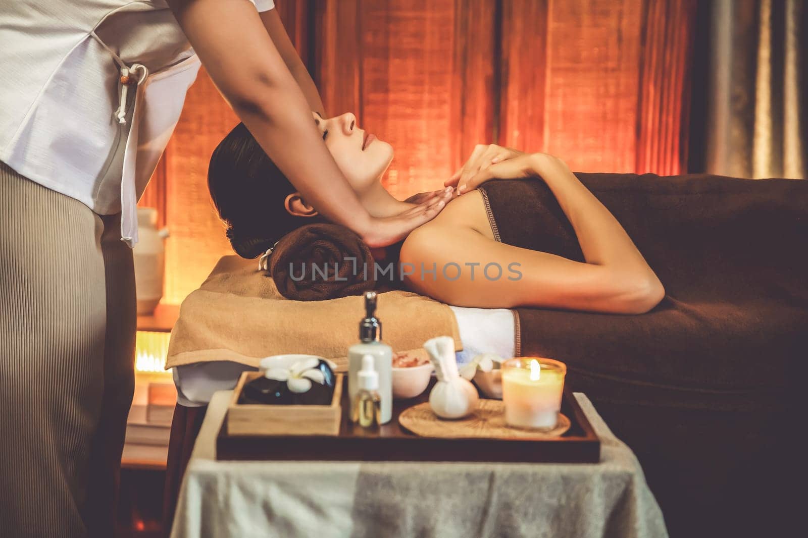 Caucasian woman customer enjoying relaxing anti-stress spa massage and pampering with beauty skin recreation leisure in warm candle lighting ambient salon spa at luxury resort or hotel. Quiescent