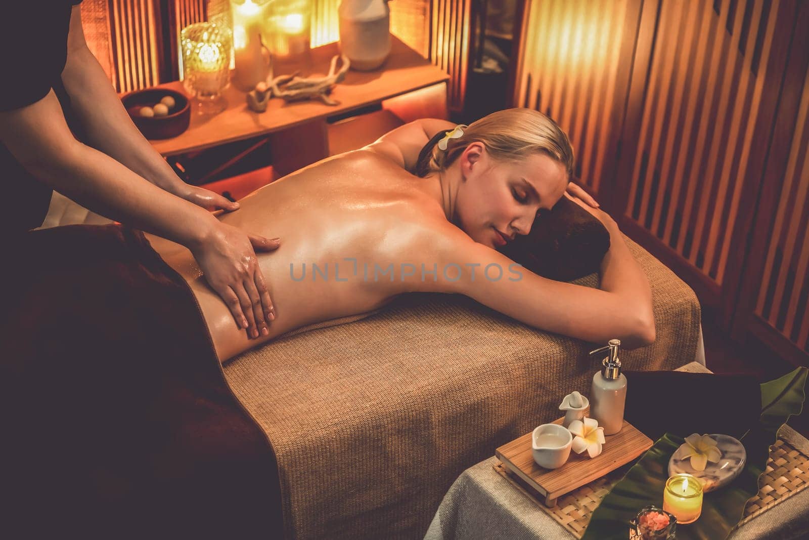 Caucasian woman customer enjoying relaxing anti-stress spa massage and pampering with beauty skin recreation leisure in warm candle lighting ambient salon spa at luxury resort or hotel. Quiescent