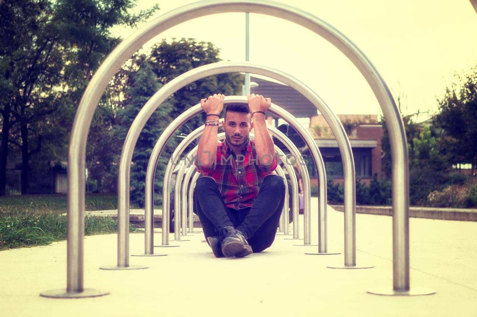 A man sitting on the ground in front of a metal structure