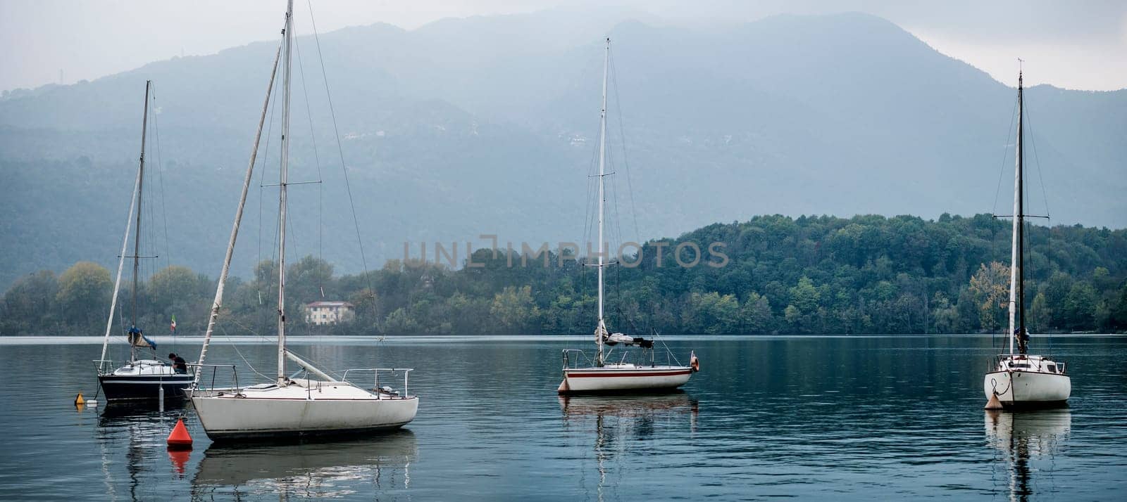 Photo of a serene lake with a fleet of colorful boats peacefully gliding on the water by artofphoto