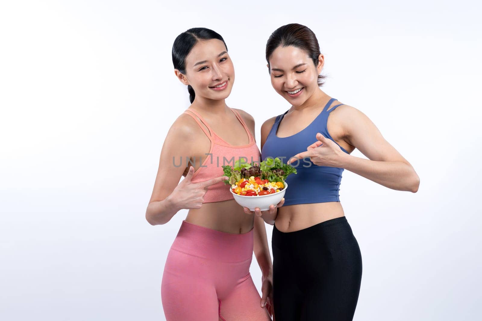 Asian woman in sportswear holding salad bowl on isolated background. Vigorous by biancoblue