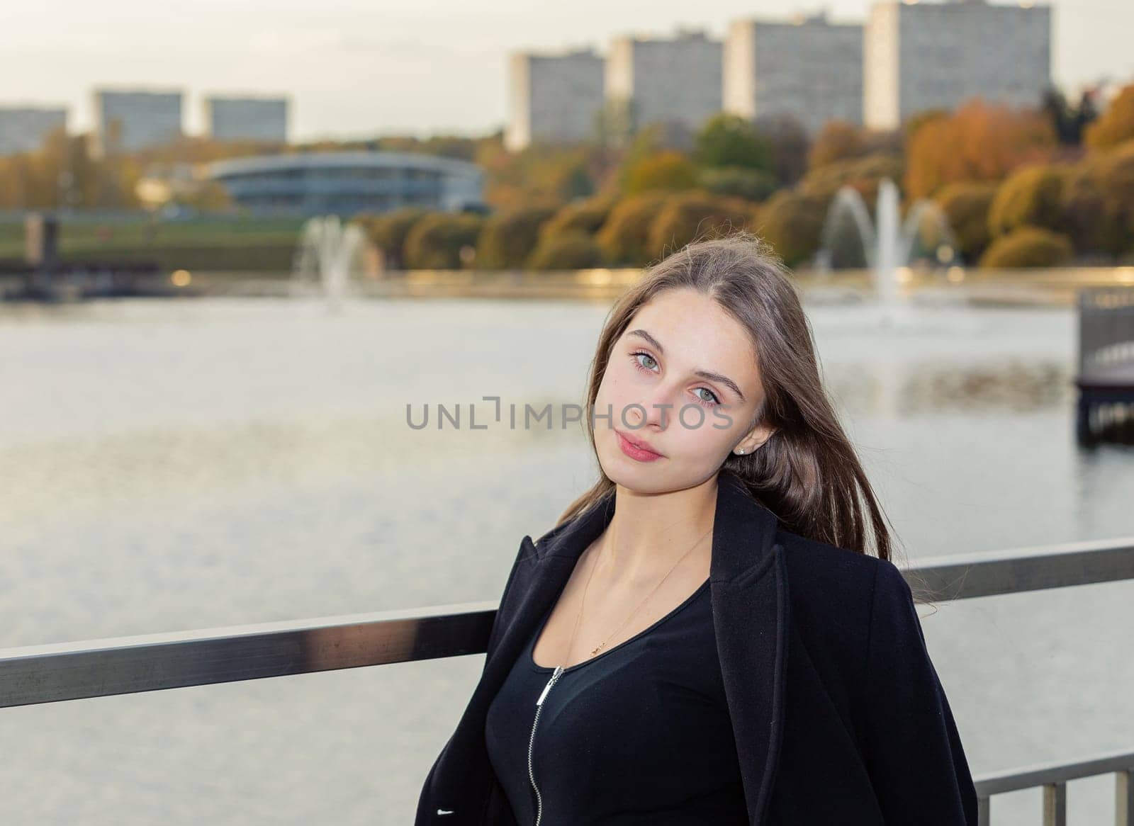 Portrait of a girl on a bridge near a pond in a city park against the backdrop of fountains