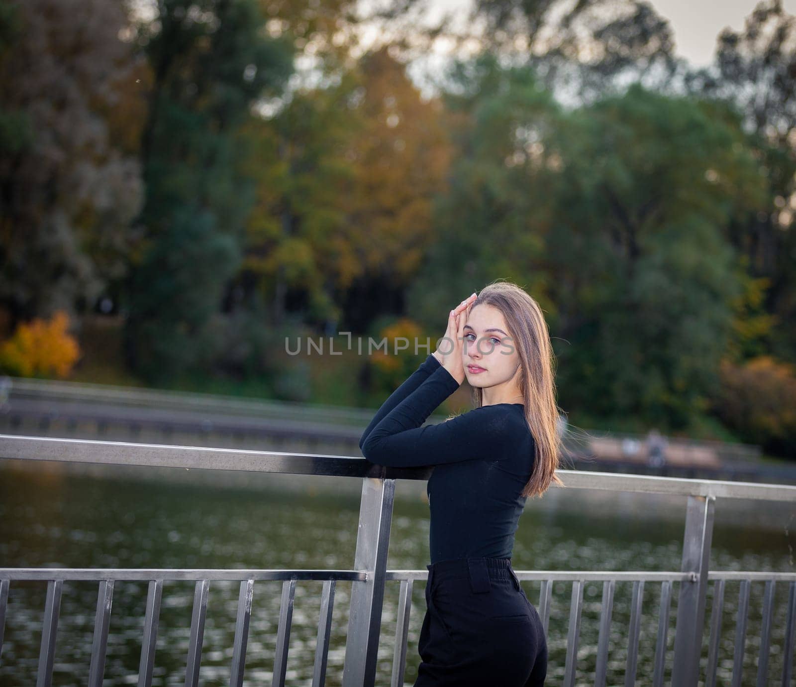 Portrait of a beautiful girl near a pond in a city park