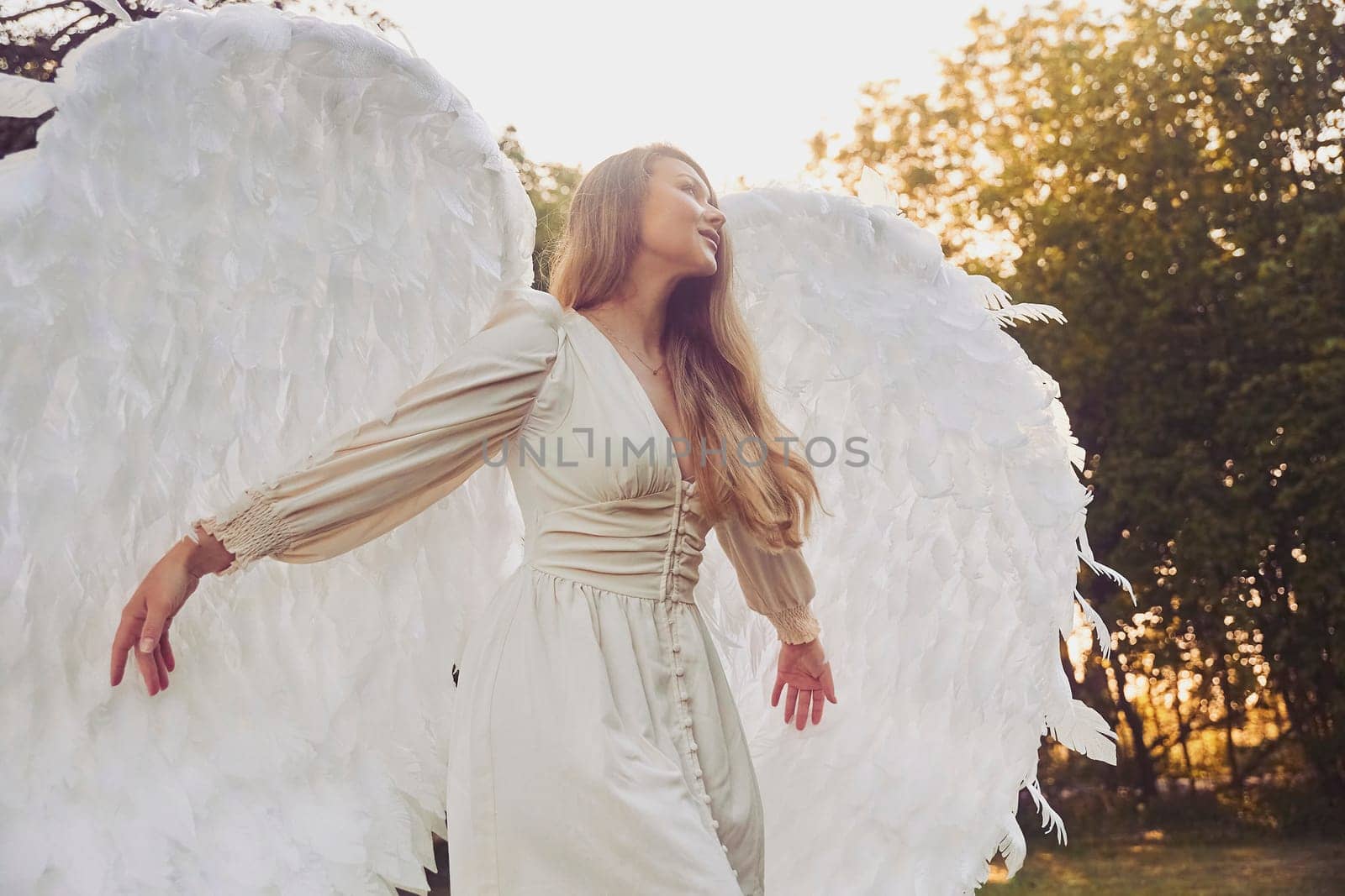 Beautiful girl dressed as an angel in the evening garden.