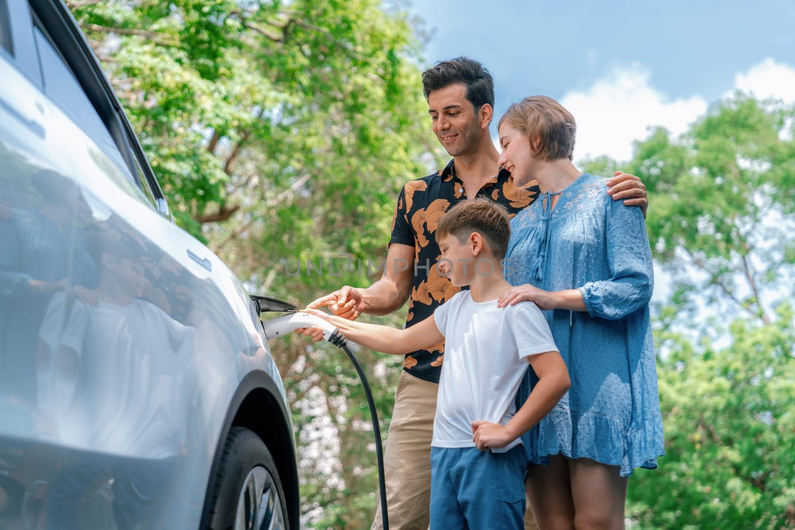 Family road trip vacation with electric vehicle, lovely family recharge EV car with green and clean energy. Natural and eco friendly car travel for sustainable environment. Perpetual