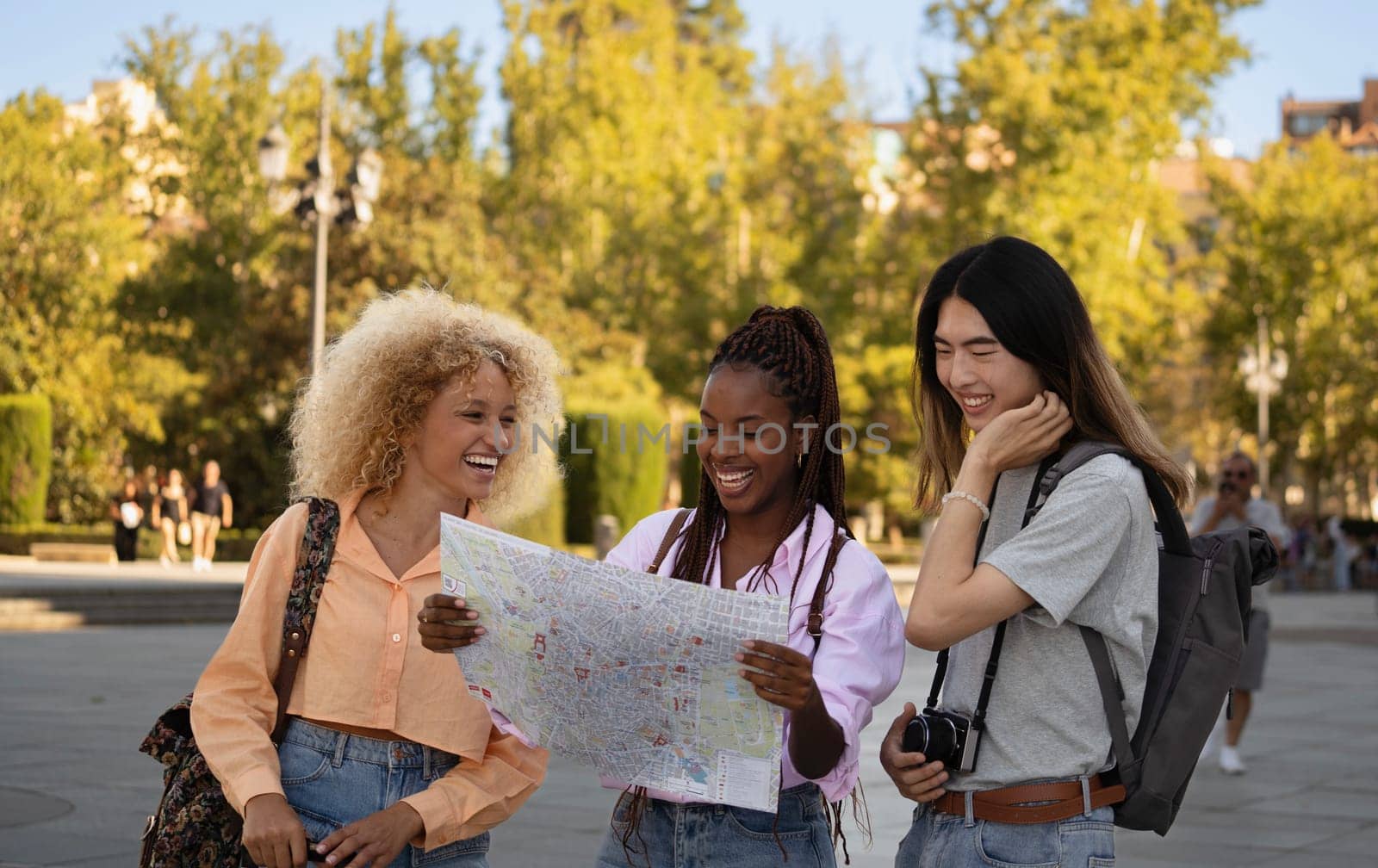 Group of multi ethnic tourists friends looking at a map and exploring Madrid city.