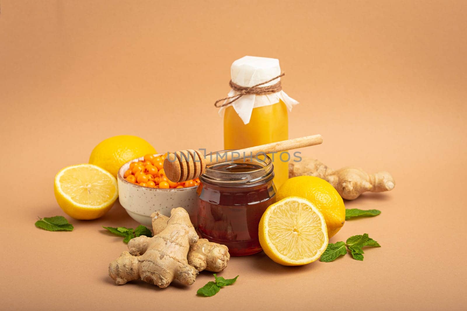 Composition with detox drink, sea buckthorn berries, lemons, mint, ginger, honey in glass jar. Food for immunity stimulation and against flu. Healthy natural remedies to boost immune system by its_al_dente