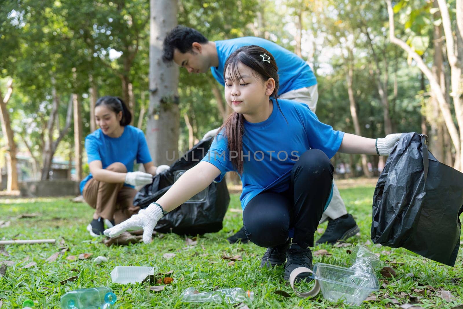 A family actively volunteering in a park, picking up litter and promoting environmental care and community service.