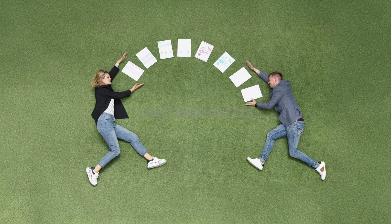 Between a man and a woman documents in a semicircle on a green cover, close-up, top view. Freelance collaboration, team concept