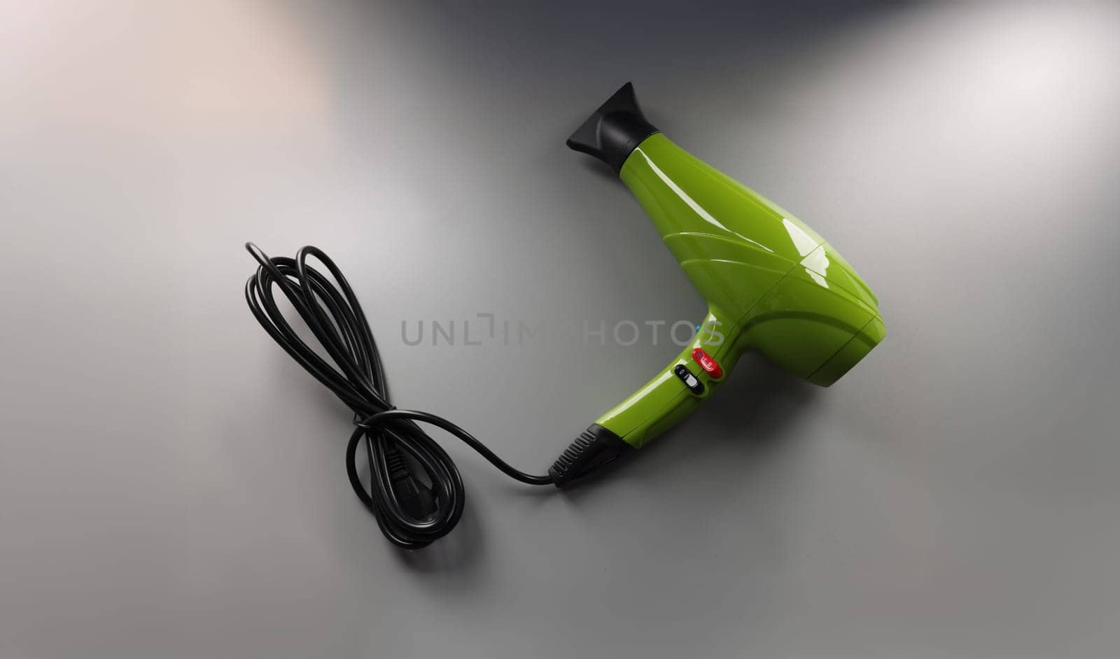 Green hair dryer on a gray background, top view, close-up. Professional equipment for a hairdresser, hair styling
