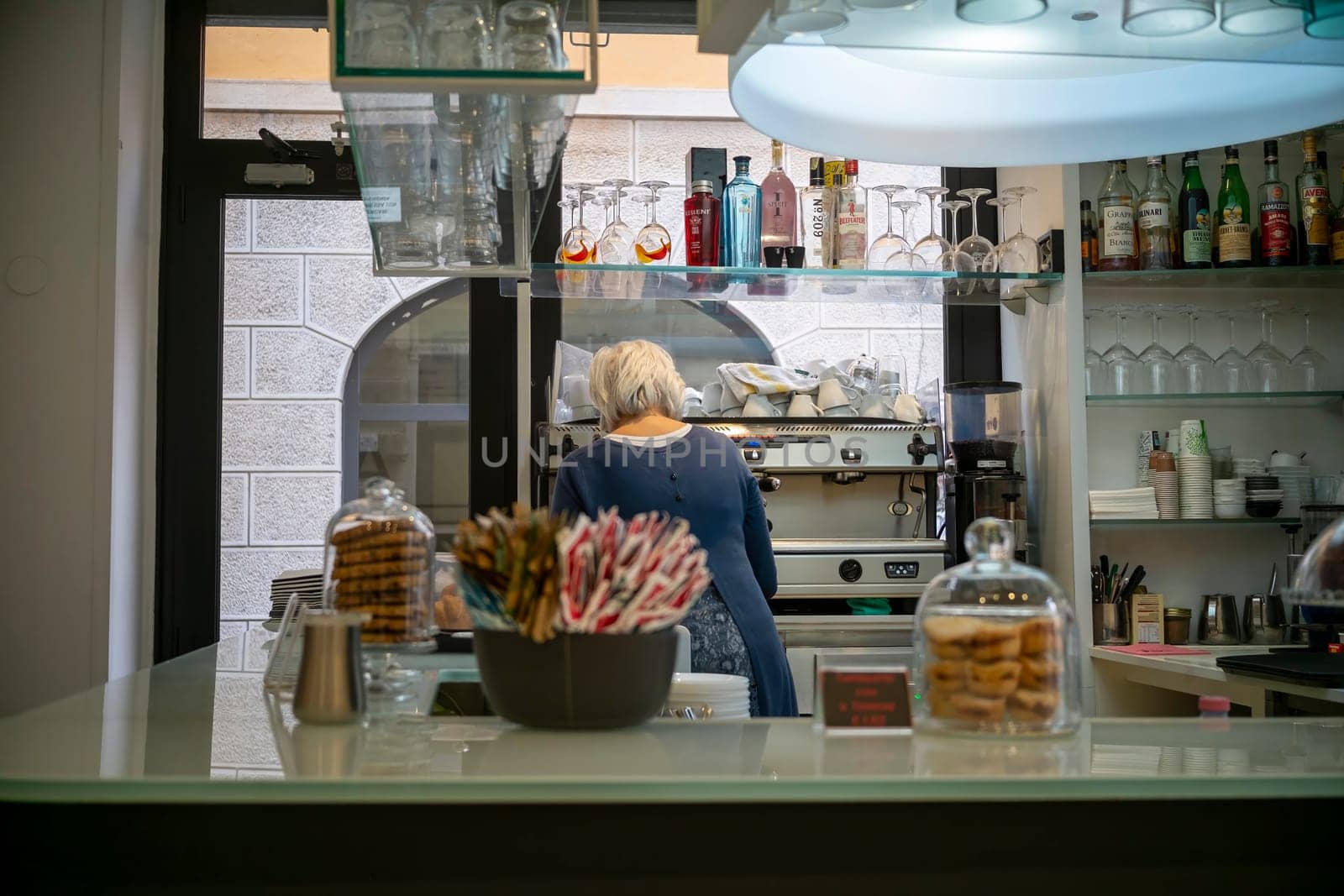 Cremona, Italy - November 20th 2024 Barista working at the counter of a traditional cafe in cremona, italy, preparing beverages and serving pastries