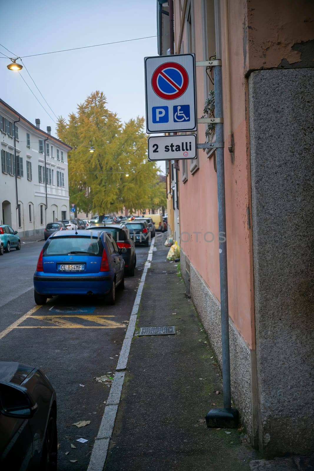 Lombardy, Italy - November 20th 2024 Blue citroen c3 pluriel parked near a sign indicating a reserved parking for disabled people in a residential street