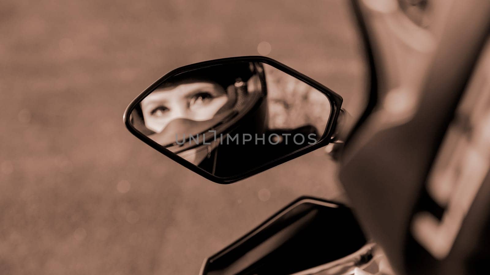 The girl on motorcycle. Blurred reflection in mirror. Selective focus. Colour of the year Mocha Mousse. Displaying girls in the mirror of the motorcycle