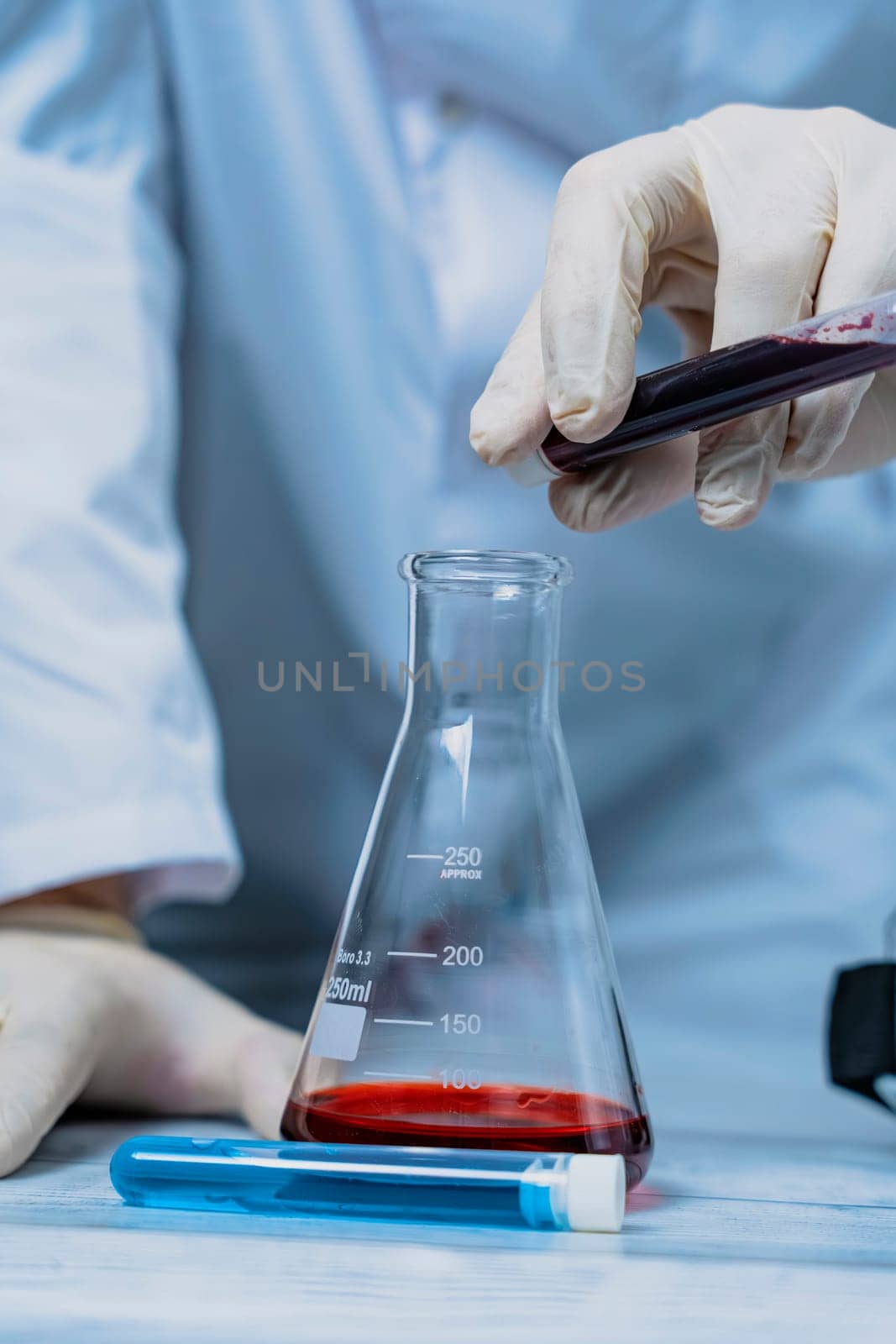 A scientist holds a test tube filled with green liquid in a laboratory, surrounded by various lab equipment. The image highlights the focus and precision involved in scientific research