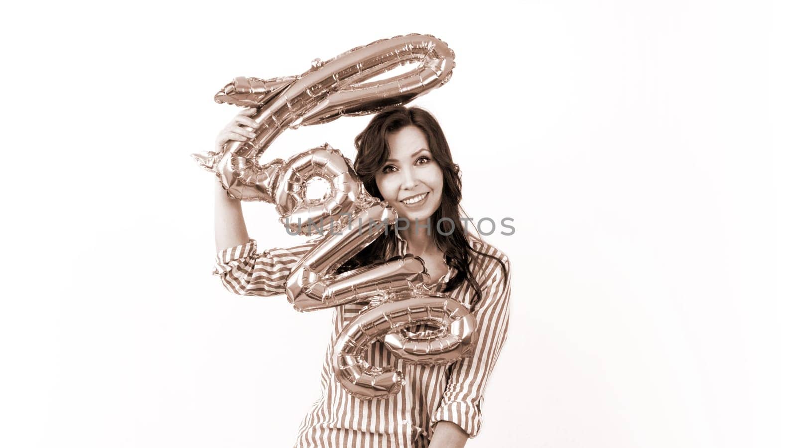 Smiling woman holding a gold balloon in the shape of the word love. Colour of the year Mocha Mousse.