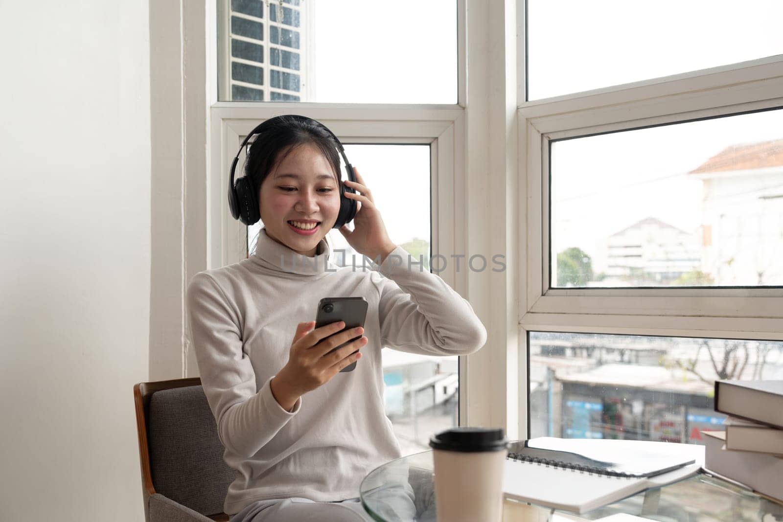 Asian beautiful woman smile at home in headphones. young woman listen music on smartphone at home. Use technology, lifestyle concept.