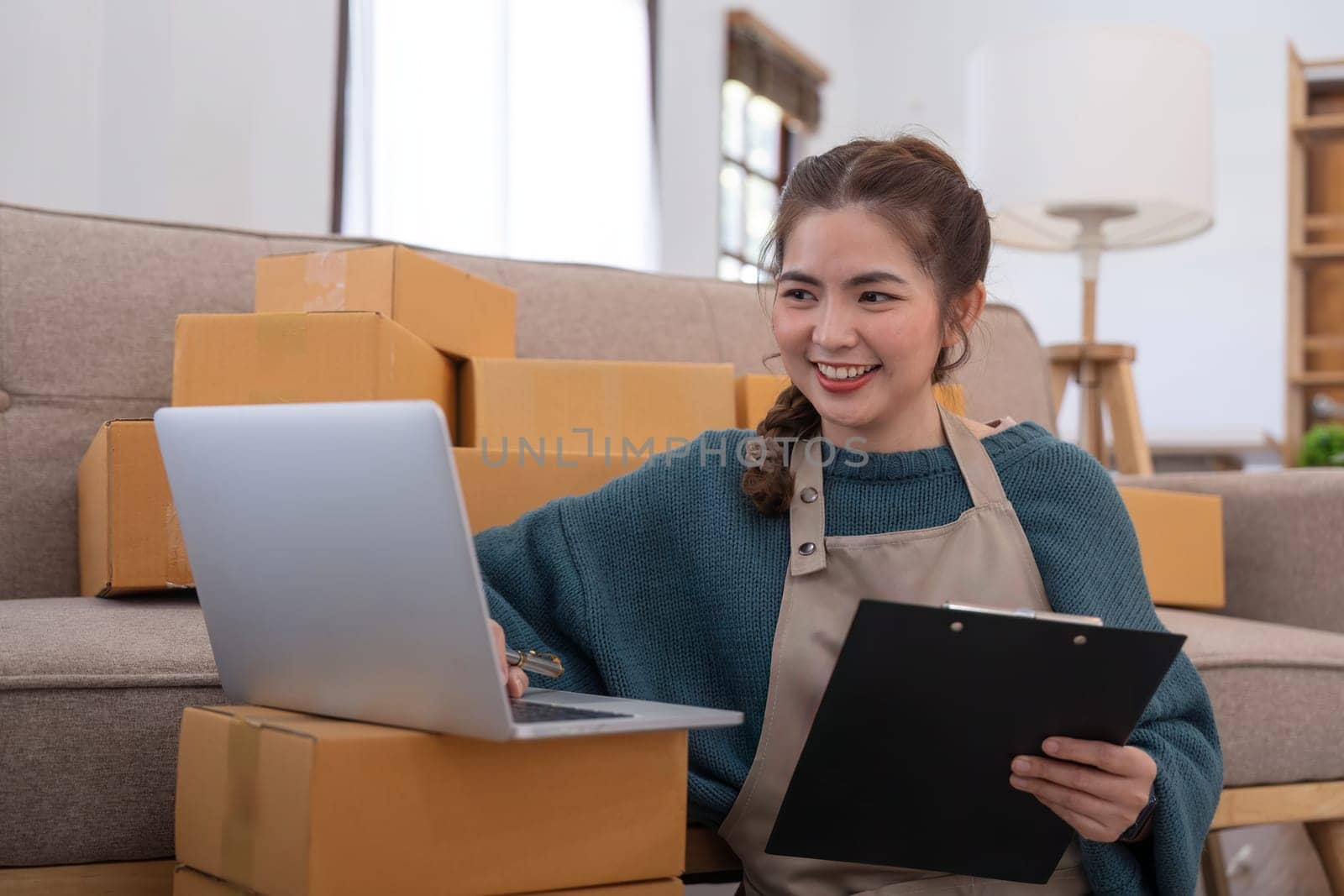 Young woman working online ecommerce shopping at her shop. Young woman seller prepare parcel box of product for deliver to customer. Online selling, ecommerce. Selling products online.