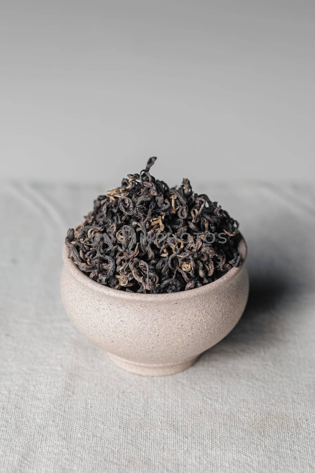 A beautiful closeup of a variety of dried tea leaves artfully displayed in a chic and stylish ceramic bowl