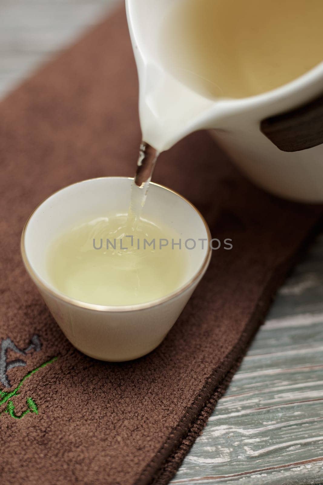 A serene and peaceful scene of tea being poured elegantly from a teapot into a fine cup on a textured background
