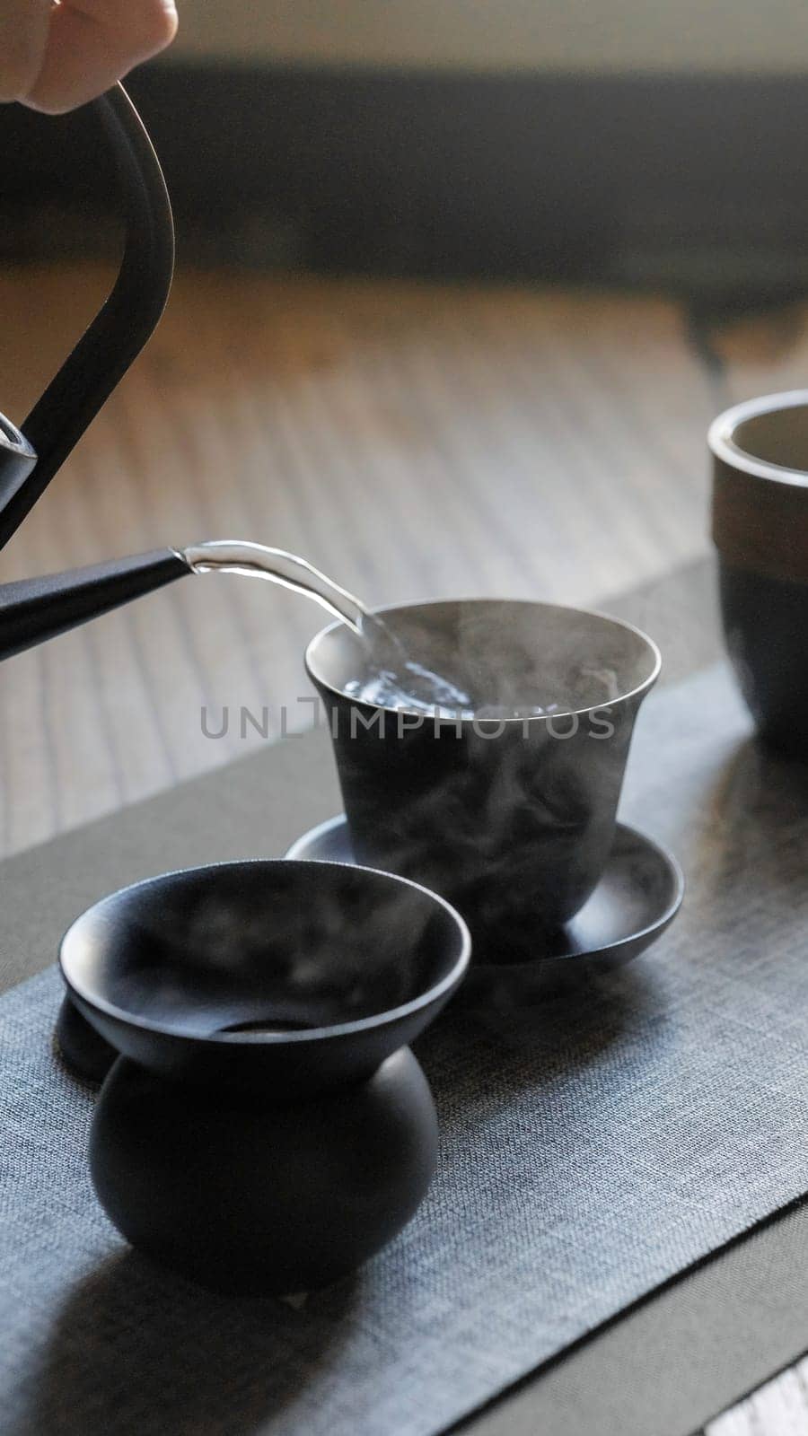 A tranquil scene of tea brewing that showcases elegant black ceramic teaware and steaming hot water