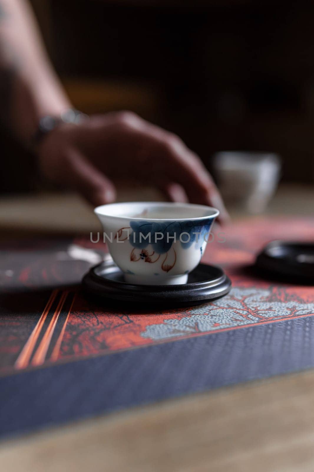 Savor the calmness while sipping a delightful cup of tea from a beautifully handcrafted vessel on a traditional surface