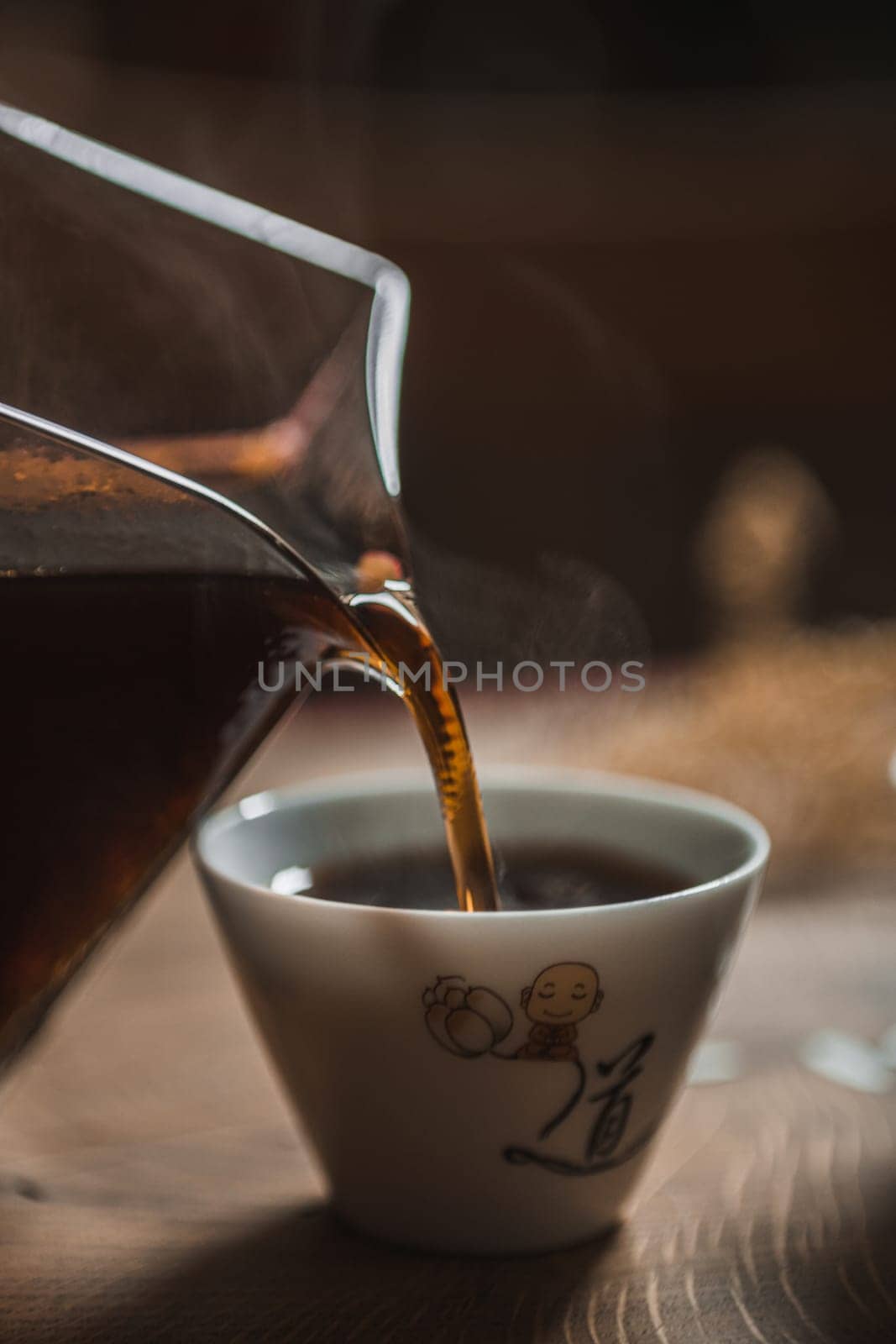 This is a closeup image of rich coffee being poured from a stylish pitcher into a steaming hot cup