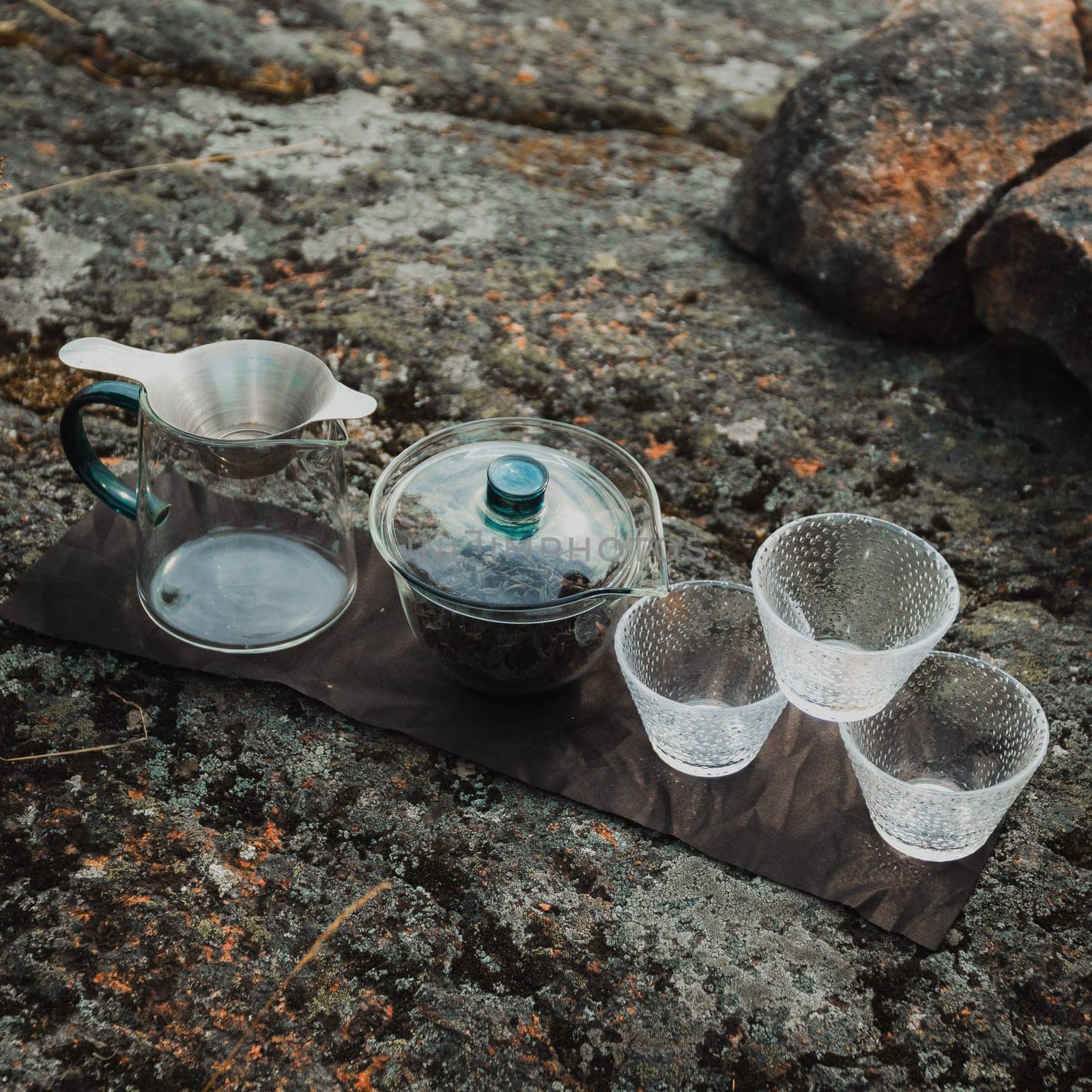 A serene tea setup situated on a rocky surface, showcasing elegant glassware designed for a perfect brew experience