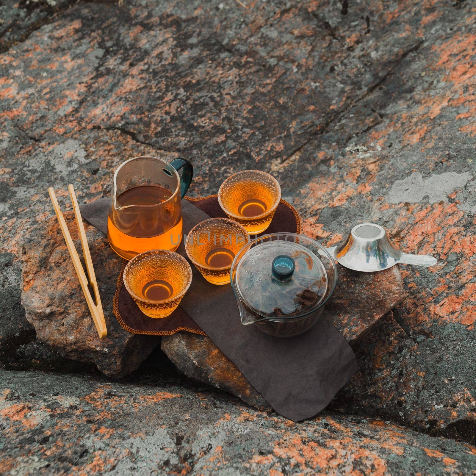 A tranquil tea setup with cups and pot on a rocky background, perfect for relaxation and nature vibes.