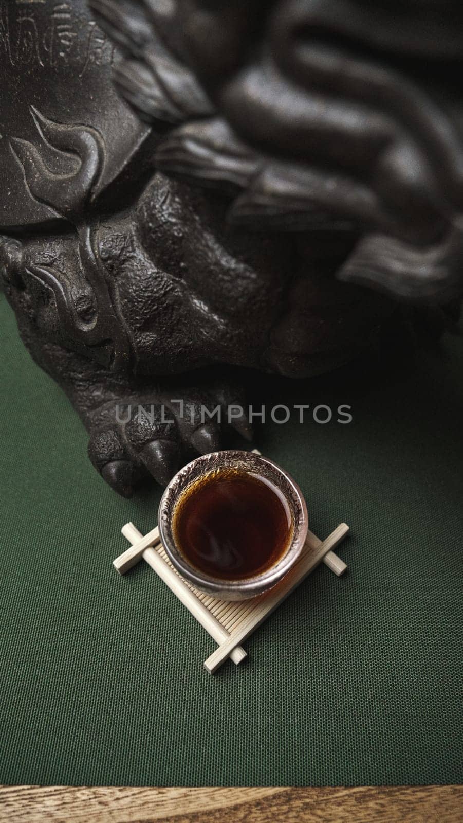A serene image shows a steaming cup of tea on a wooden stand next to an intricate, beautiful sculpture