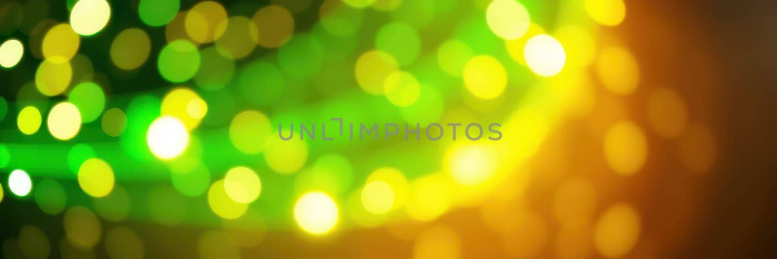 Bright bokeh lights shimmer in a blend of green and yellow hues, adding vibrant energy to an outdoor festival happening at night with people enjoying the celebration.