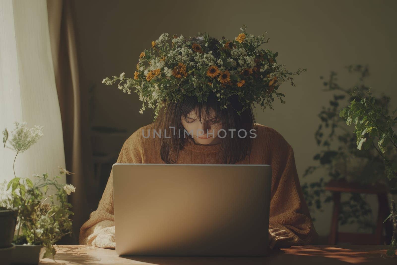A young woman sits at a wooden table working on her laptop, adorned with a floral crown. Surrounded by greenery, this cozy indoor space exudes tranquility and creativity.