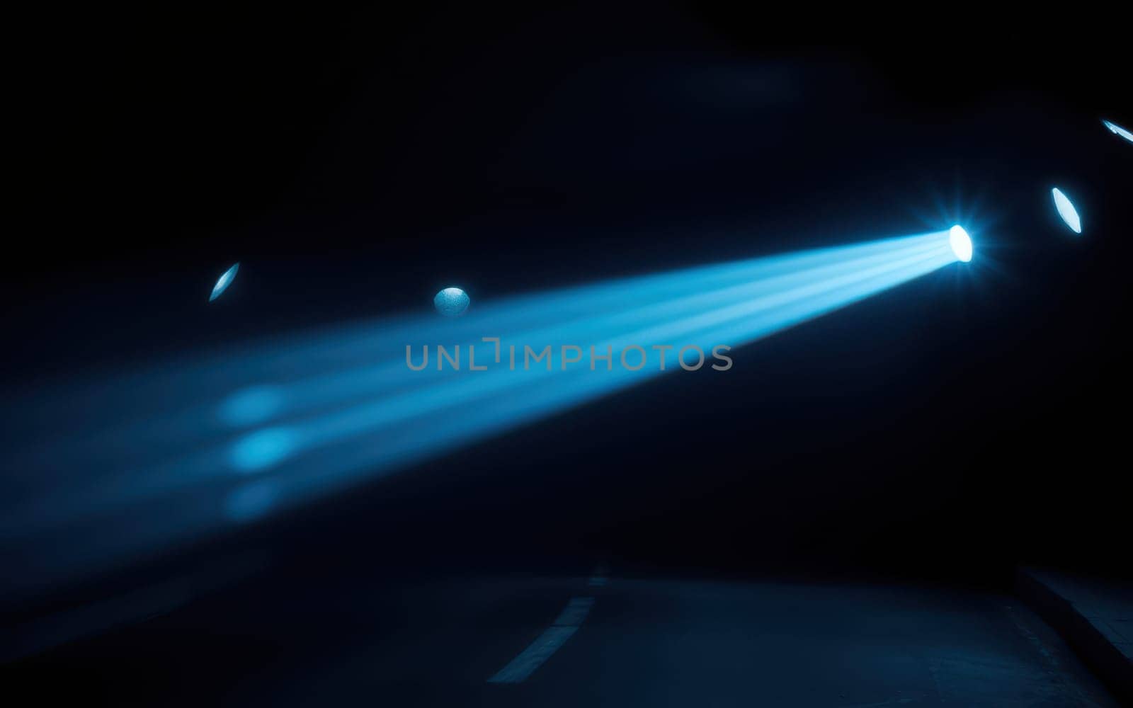 Amidst darkness, bright blue beams of light cut through the night, illuminating a dimly lit road. The contrast creates an intriguing, moody ambiance perfect for nighttime exploration.