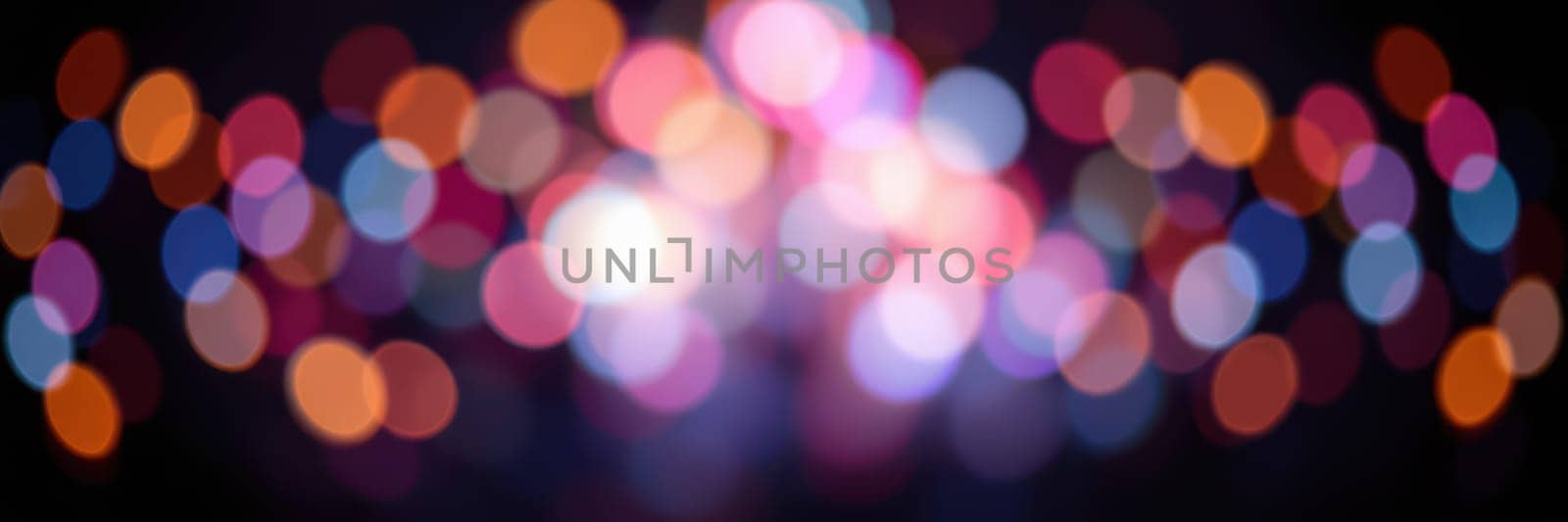 Bright and colorful bokeh lights fill the background, creating a lively and cheerful atmosphere during a nighttime event. The vibrant hues enhance the festive mood.