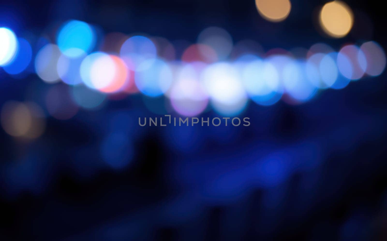 Colorful and blurred lights create a dreamy effect, illuminating the urban environment at night. The atmosphere is lively with hints of joy and celebration in the air.