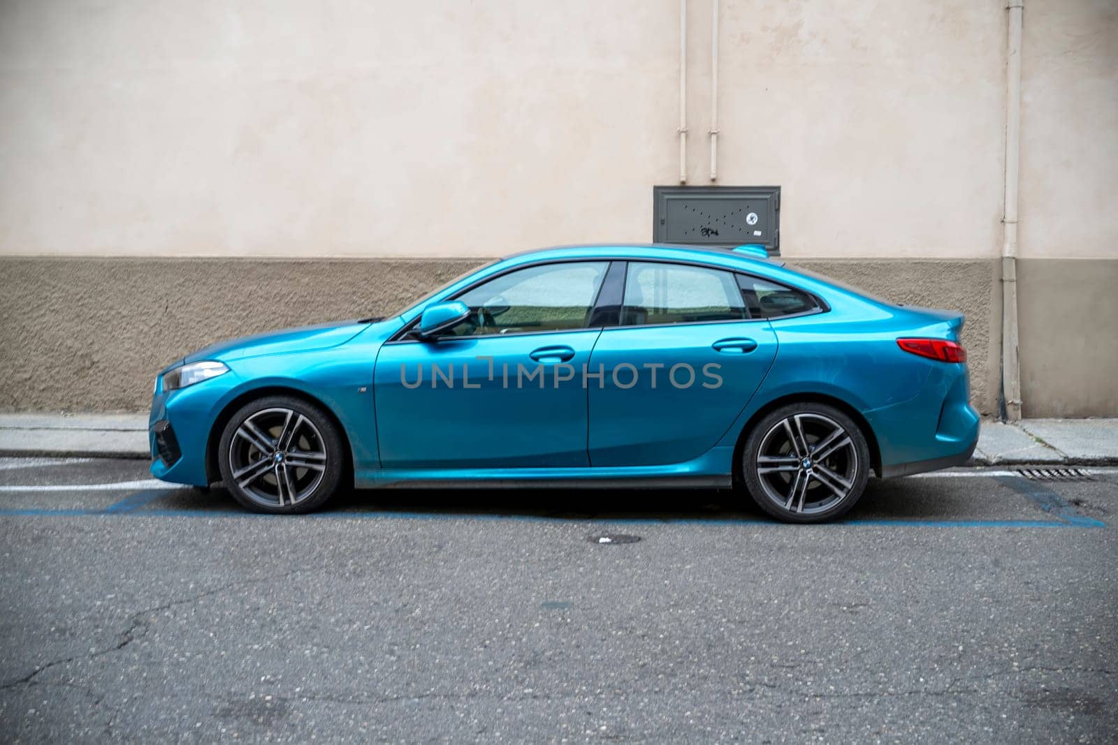 Lombardy, Italy - November 20th 2024 Stylish snapper rocks blue metallic bmw 218i gran coupe parked on a european city street