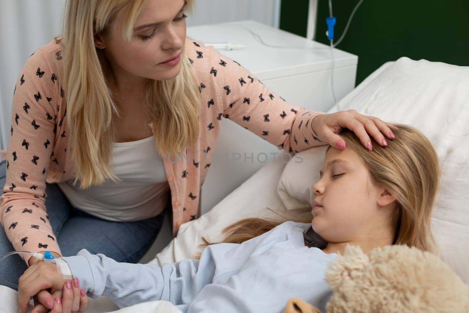 A loving mother holds her daughters hand, offering comfort and support during a tough hospital stay