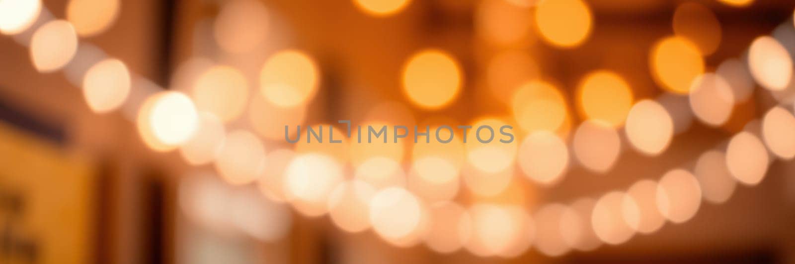 Warm golden lights illuminate a cozy indoor setting, creating an inviting atmosphere for a gathering. The soft glow enhances the ambiance as guests mingle and enjoy the moment.