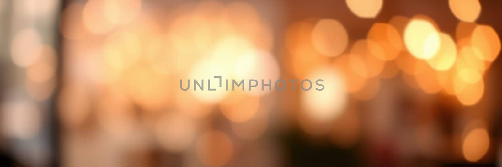 Soft golden lights illuminate a cozy space, creating a warm and inviting ambiance as patrons engage in lively conversations at a cafe in the evening.