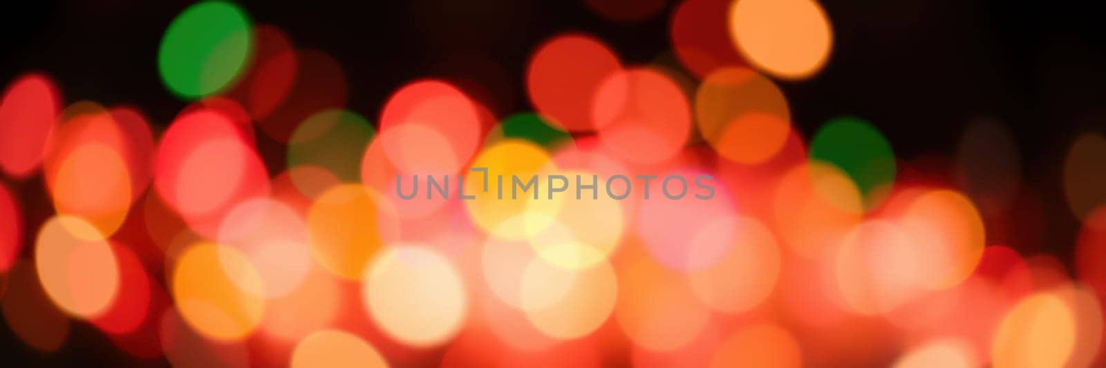 Soft, blurred circles of light in various colors create a warm, festive atmosphere at a nighttime event, enhancing the joyful spirit of the holiday season.