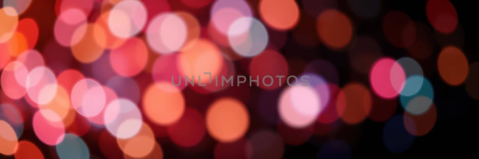 Vibrant bokeh lights in shades of red, pink, and blue illuminate the night, enhancing the joyful atmosphere of an urban celebration filled with excitement and energy.