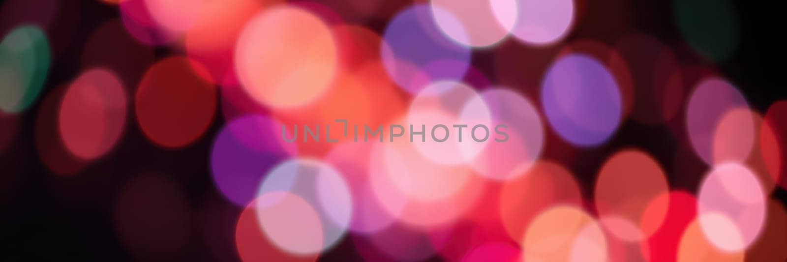 Vibrant bokeh lights in shades of red, purple, and blue illuminate a festive setting, enhancing the celebratory mood of a city event at night.