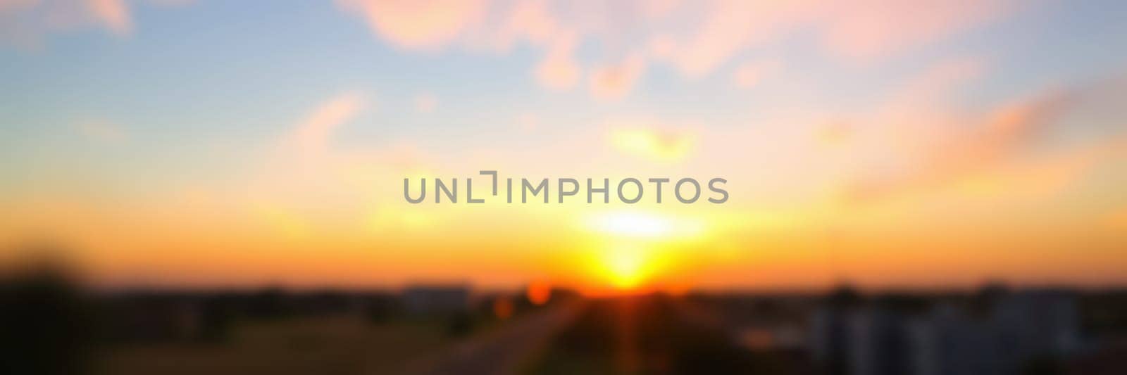 A breathtaking sunset captures the sky in shades of orange, pink, and purple, as the sun dips below a city skyline, marking the end of a peaceful day.