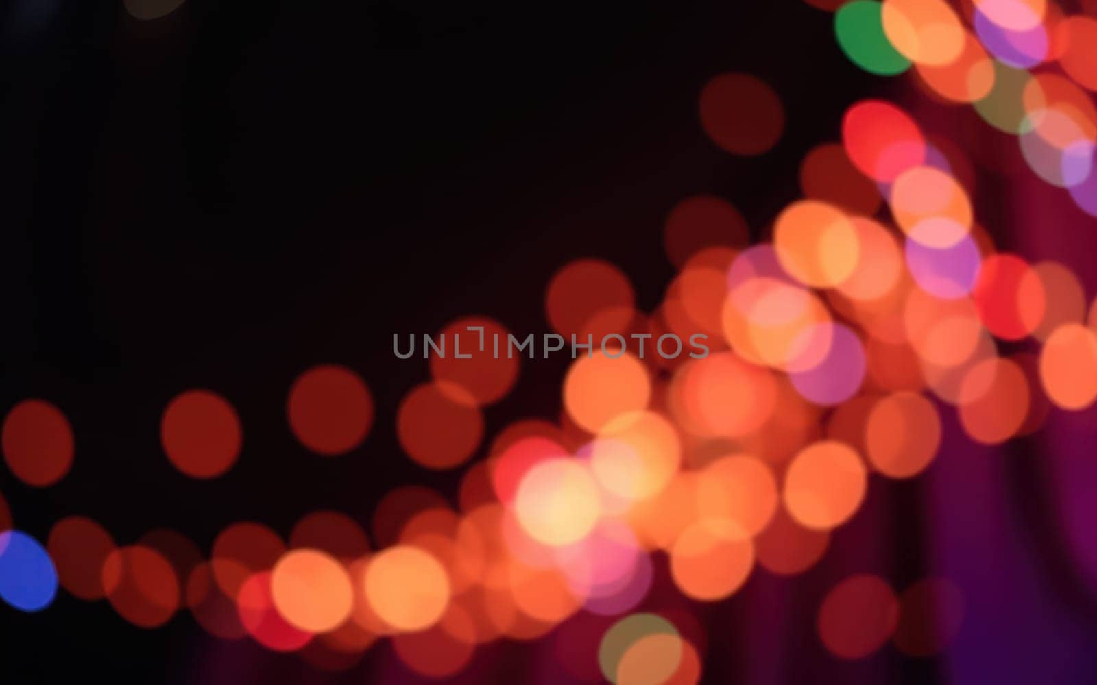 Colorful bokeh lights twinkle in a blurred background, creating a magical ambiance at an evening celebration in a bustling urban setting.