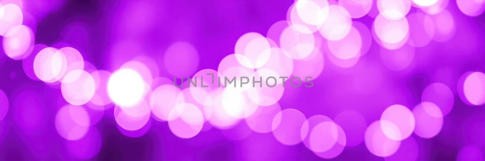 Soft purple bokeh lights illuminate a festive atmosphere in an outdoor urban location. The blurred lights create a whimsical effect, enhancing the evening ambiance.
