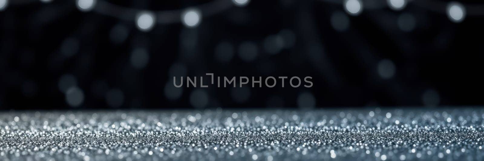 A shimmering surface is blanketed with tiny reflective particles under soft, blurred lights. The warm ambiance suggests a celebration or holiday gathering.