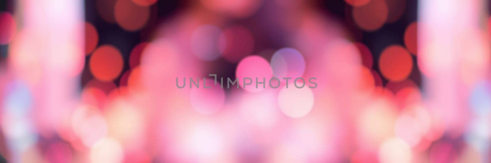 Blurred bokeh lights create a vibrant atmosphere at an energetic gathering, where attendees enjoy music and socializing amid colorful illumination.