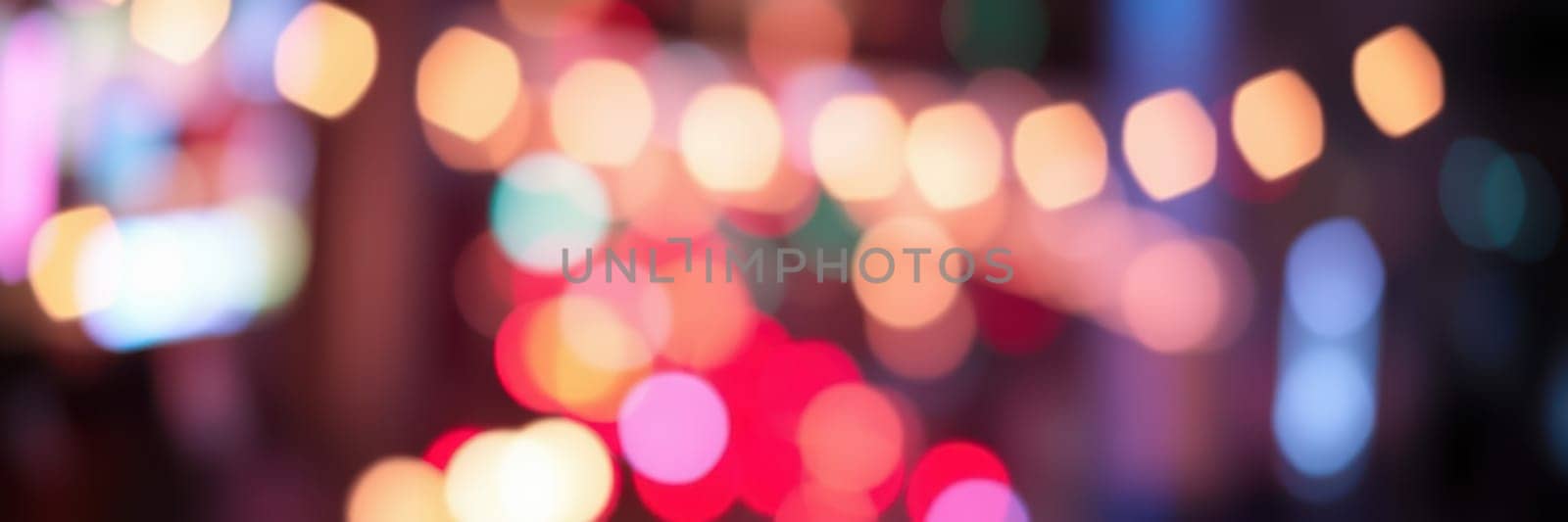 Bright, colorful bokeh lights fill the urban setting, creating a vibrant and dynamic atmosphere during the evening hours. The street is alive with energy and excitement.