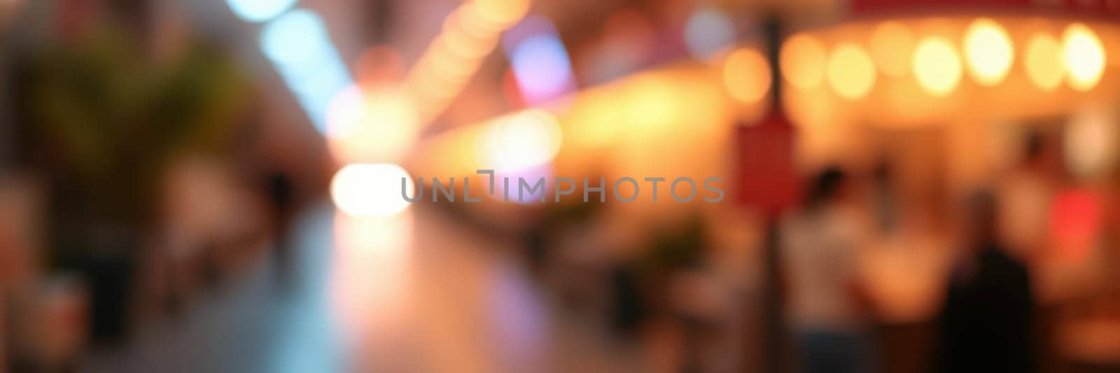 A lively market street filled with bright lights and blurred activity, showcasing local vendors and visitors enjoying the vibrant atmosphere during the evening.