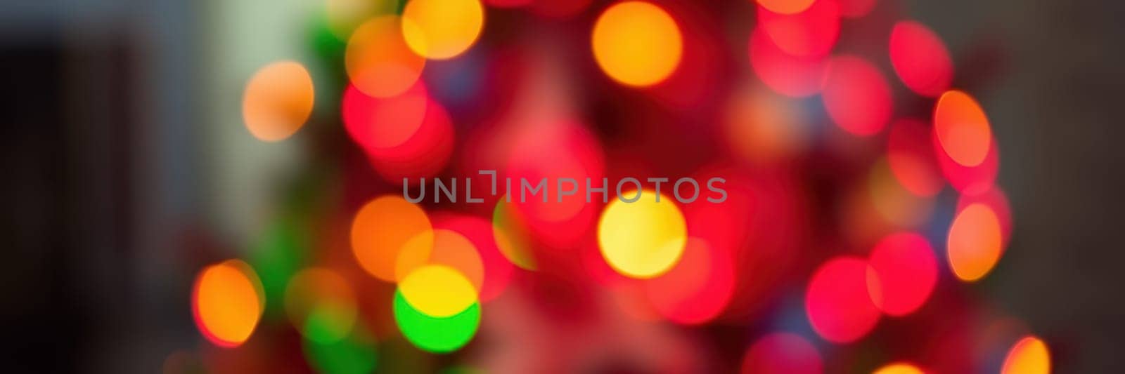 Brightly colored lights adorn a Christmas tree, illuminating the cozy indoor space where family members enjoy a joyful winter gathering filled with laughter and warmth.