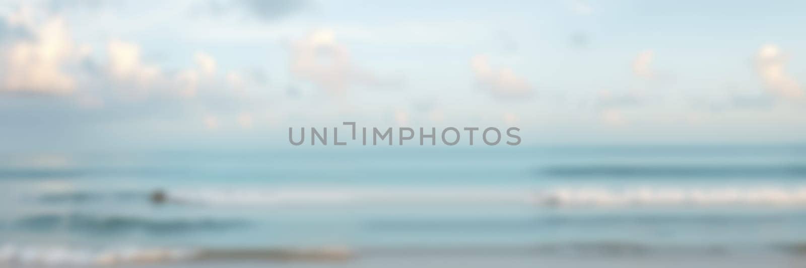 Early morning at a tranquil beach where calm waves lap against the shore and soft clouds float in the bright blue sky. A peaceful natural setting for reflection and relaxation.